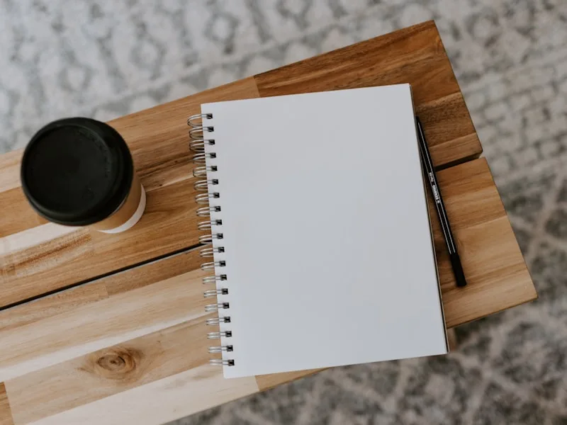 Minimalistische werkruimte met open notitieboek en pen op een houten bureau