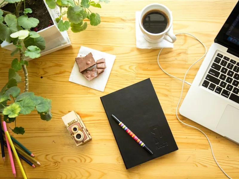 Koffiekop en dagplanner op een bureau bij een open raam met daglicht